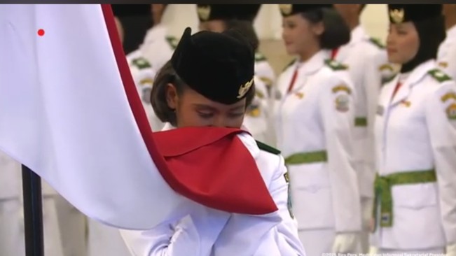 Rhita Lovely Chantika Febiolla Ayomi, anggota Paskibraka dari Papua Barat mencium bendera Merah Putih. [YouTube Sekretariat Presiden]